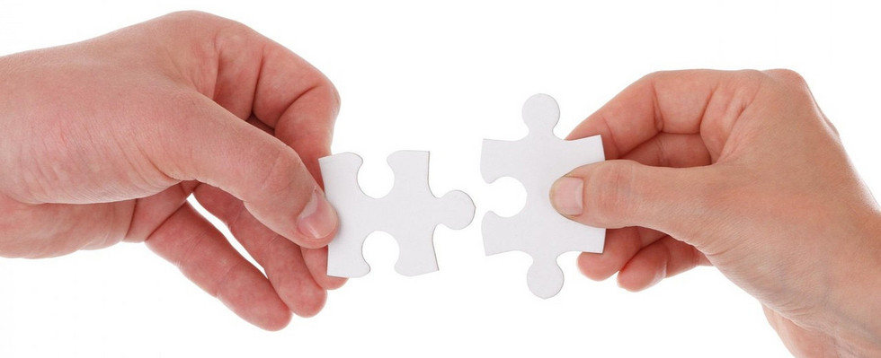 Zwei Hände fügen zwei Puzzleteile ineinander